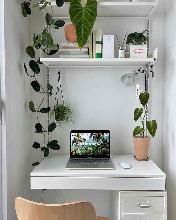 White-toned veranda home office featuring desk, drawer cabinet, hanging plants, and diffuser in a simple modern setting