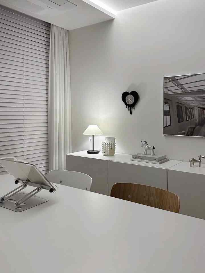 白とナチュラルカラーの書斎、デスクとテーブルランプが配置された雰囲気のあるインテリア