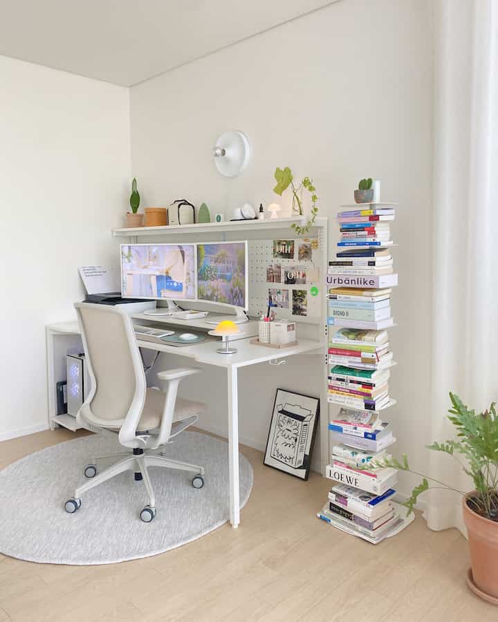 A white and natural-toned study featuring desk, ergonomic chair, book tower, and plants in a clean home office setup