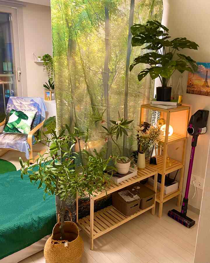 Natural style living room with a forest-themed curtain backdrop, featuring plants and wooden shelves in a cozy atmosphere