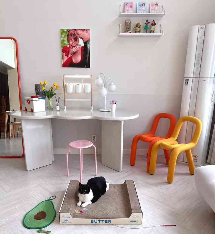 ホワイトとナチュラルカラーが調和したリビング、猫用スクラッチャーとおもちゃが配置されたペットに優しいインテリア