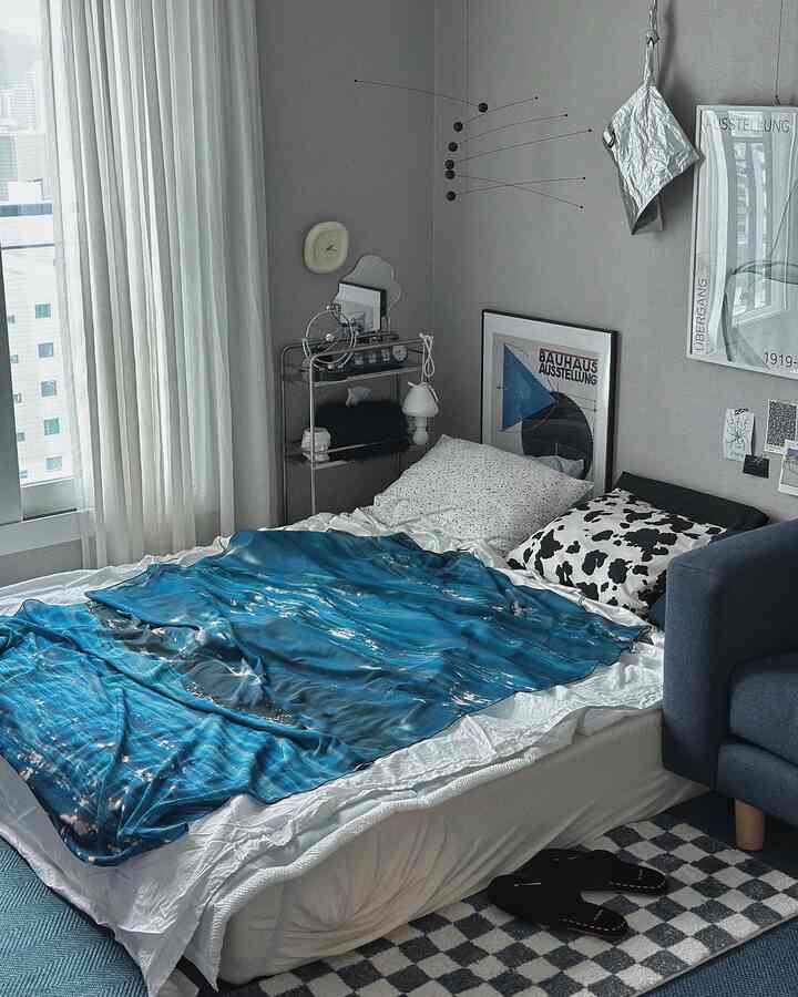 Serene blue and gray toned studio bedroom featuring a centrally placed bed and modern furnishings creating a cozy atmosphere