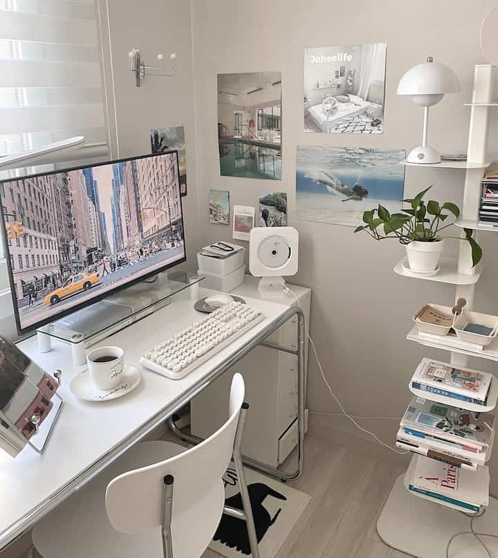 White-toned home office space featuring a computer desk, chair, and wall posters with a clean minimalist vibe