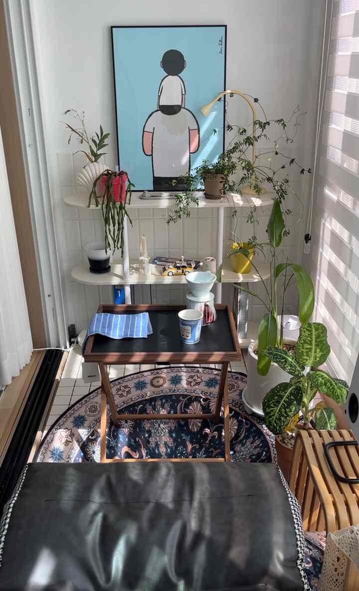 白い背景に木目調家具と植物、コーヒー用品がある小さなリビングスペース