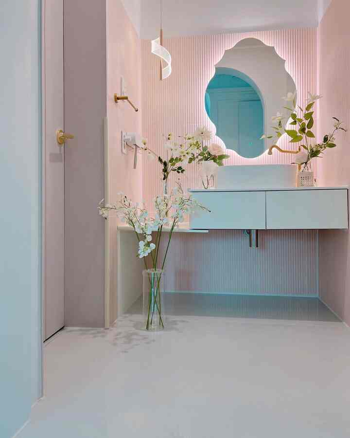 Bathroom with soft pink walls featuring a dry sink and backlit decorative mirror, complemented by white cabinetry in a modern style