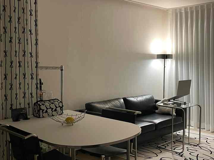 モダンな白と黒のトーンの二人暮らしのリビング、黒のレザーソファと透明なサイドテーブルが配置された空間