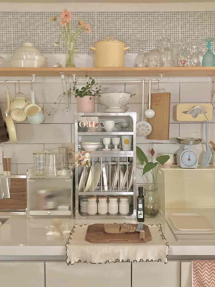 柔らかな黄色と白の色調のキッチン、調理器具と収納が整った雰囲気のあるインテリア