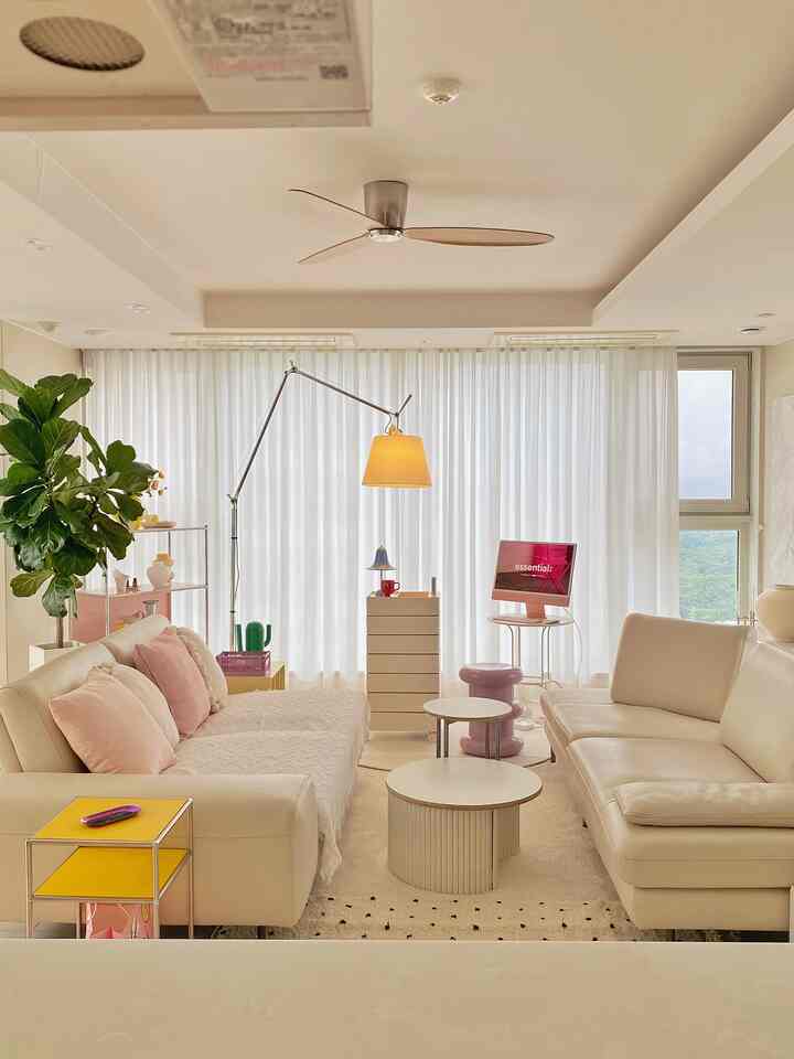 Nordic living room in white and beige tones featuring two sofas, sheer curtains, and a floor lamp, creating a calm atmosphere