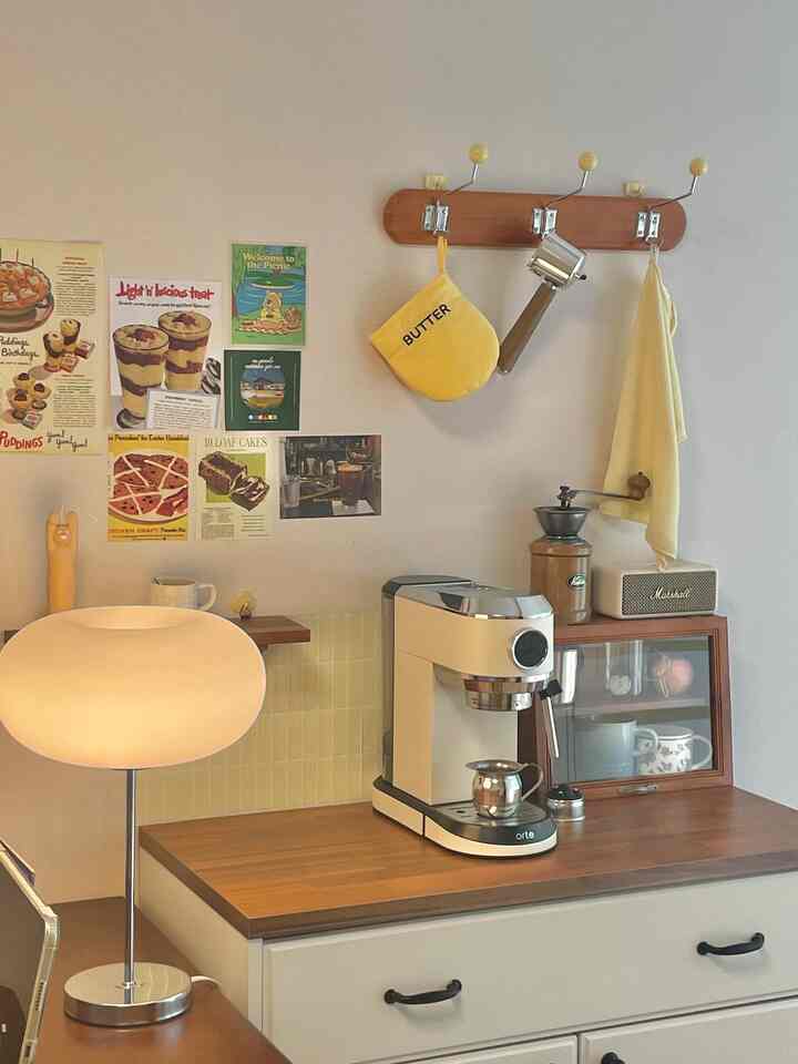 アイボリーと木目調のワンルームキッチン、エスプレッソマシンと壁の装飾が配置された雰囲気のあるおうちカフェ空間