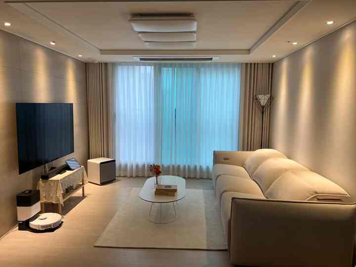 アイボリー色調のリビング、リクライナーソファとカーテン、ラグが調和したモダンな新築新婚住宅のインテリア