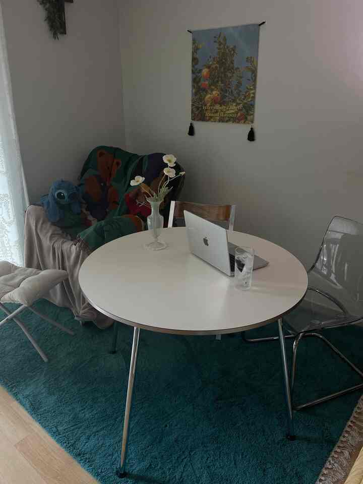 白と青の色調のダイニングルーム、丸いテーブルと椅子、壁のポスターが配置された雰囲気のあるインテリア