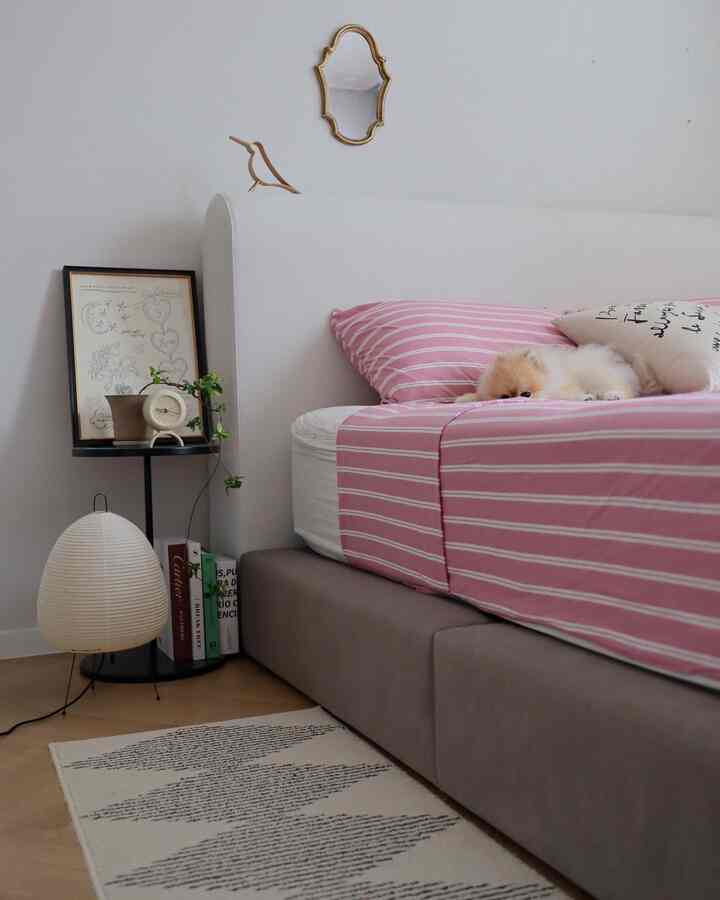Pink and gray toned bedroom featuring a cozy bed with a small dog lying peacefully