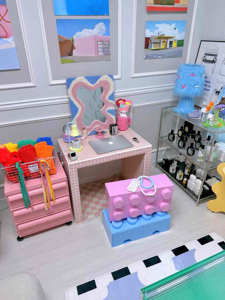 パステルピンクとブルーのトーンが特徴のリビング、ピンクのチェストとタイルのデスクが配置されたかわいいインテリア