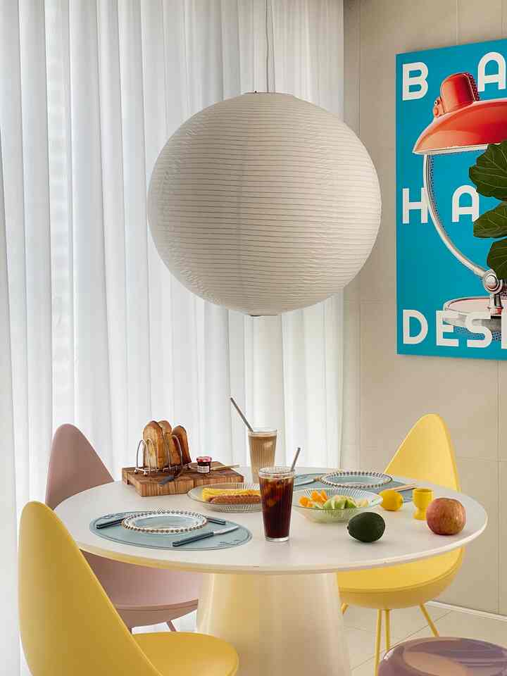 White and yellow toned dining room featuring simple round table and chairs with glassware and brunch setup creating a cozy home cafe atmosphere
