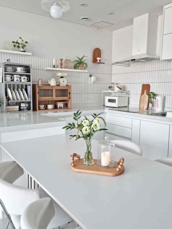 明るく白を基調としたキッチンとダイニング、木製トレイと花が配置された雰囲気のあるインテリア