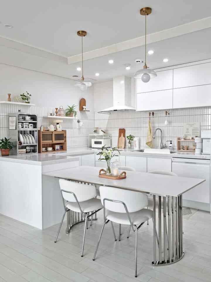 白と木目調が調和したキッチン・ダイニングルーム、モダンなダイニングテーブルとペンダントライトが配置された印象的な空間