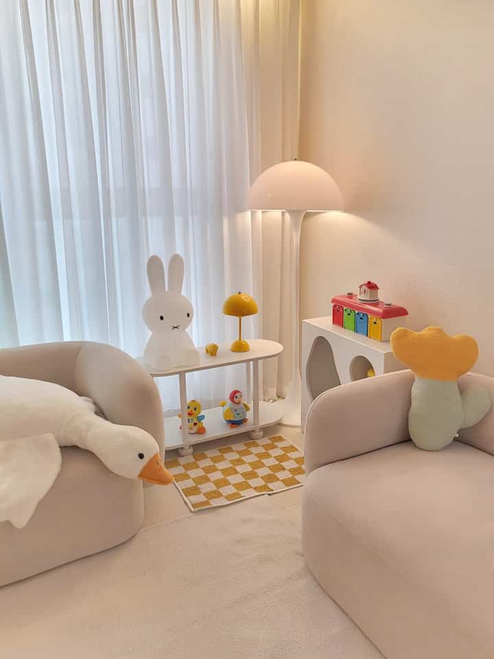 白を基調としたリビングの子供部屋、黄色のアクセントクッションと照明が温かみのある雰囲気を演出するプレイルーム