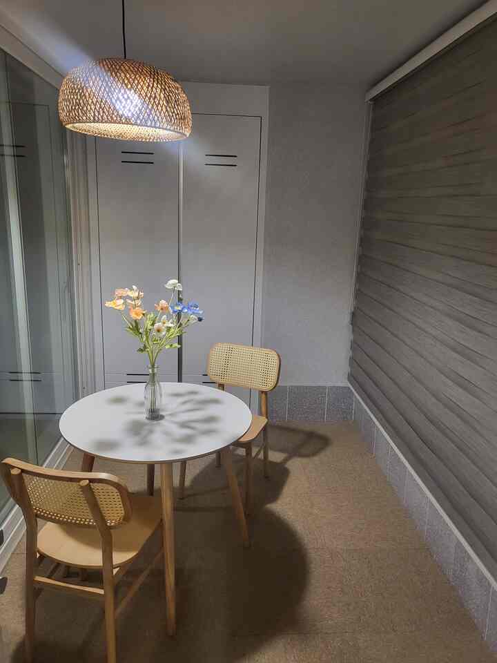 Natural toned veranda featuring a round table, rattan pendant light, and vase creating a cozy home cafe atmosphere