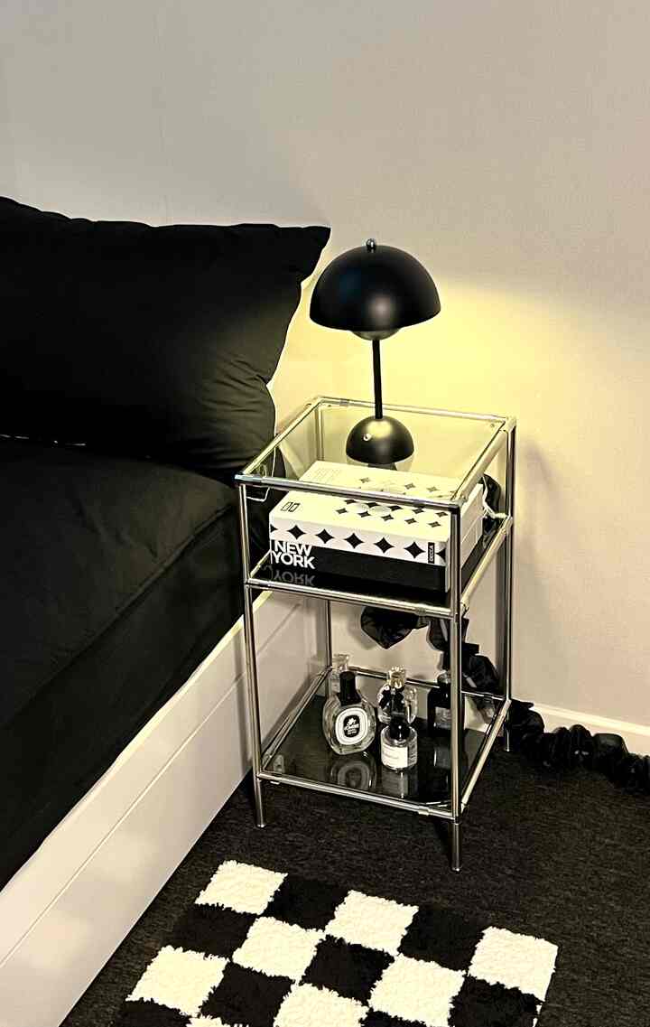 黒と白のトーンの寝室、黒い枕とワイヤレス充電ランプが配置されたモダンなワンルームのインテリア