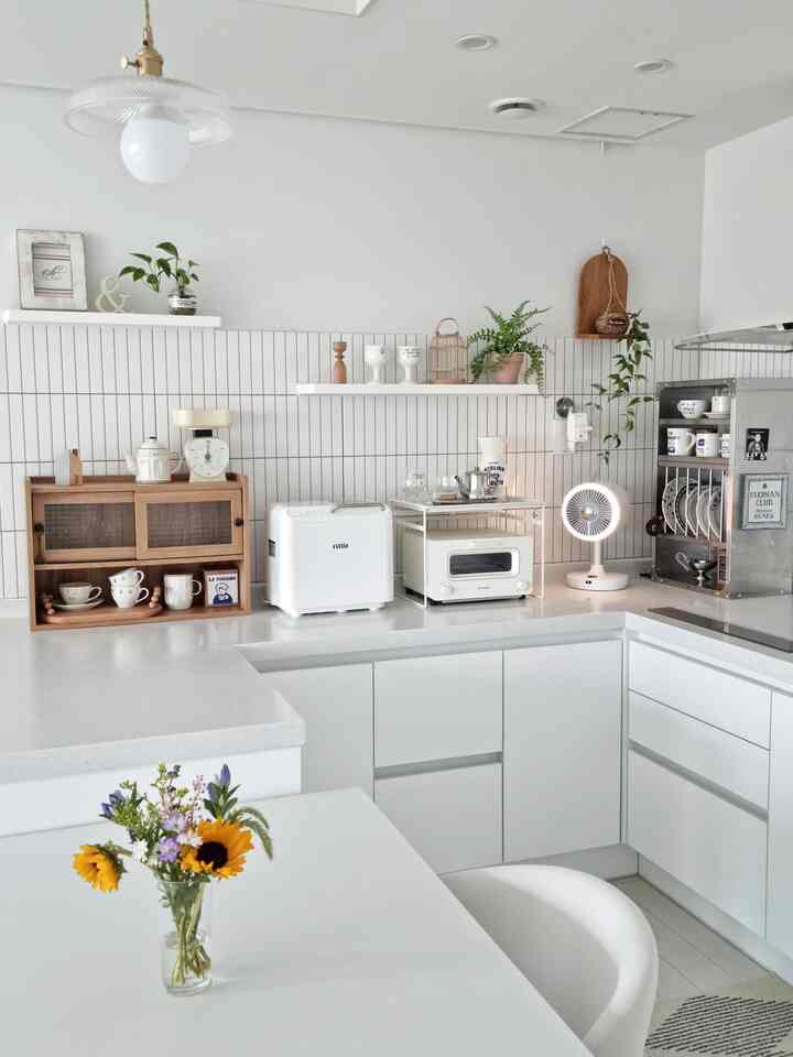Bright white-toned kitchen and dining area featuring white cabinets and wooden accessories creating a natural interior