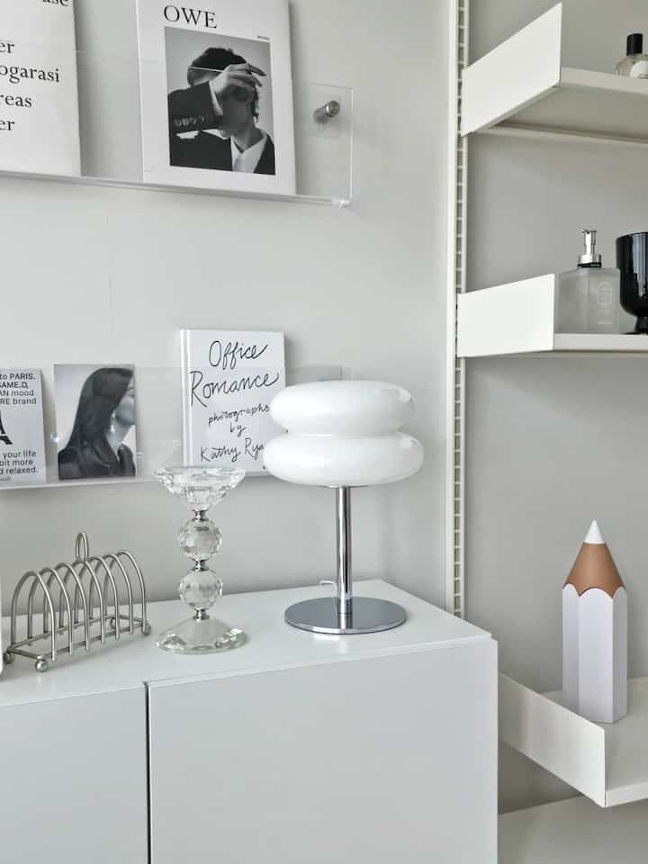 Modern white-toned studio space featuring acrylic shelves and unique lighting with a neat interior design
