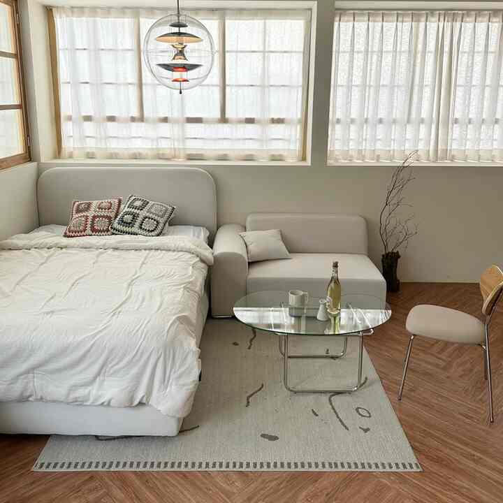 White and wood tone bedroom featuring white bed and sofa arranged in a cozy, clean space
