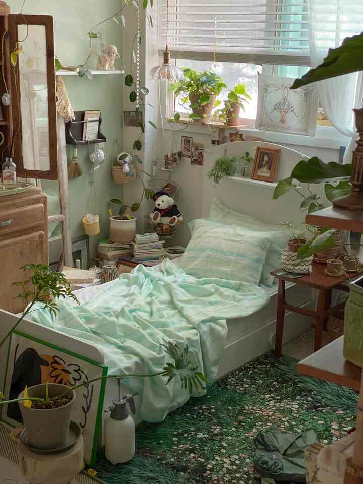 淡いミント色と木目調が調和した寝室、多数の植物と天然木のブラインドが自然な雰囲気を醸し出すインテリア