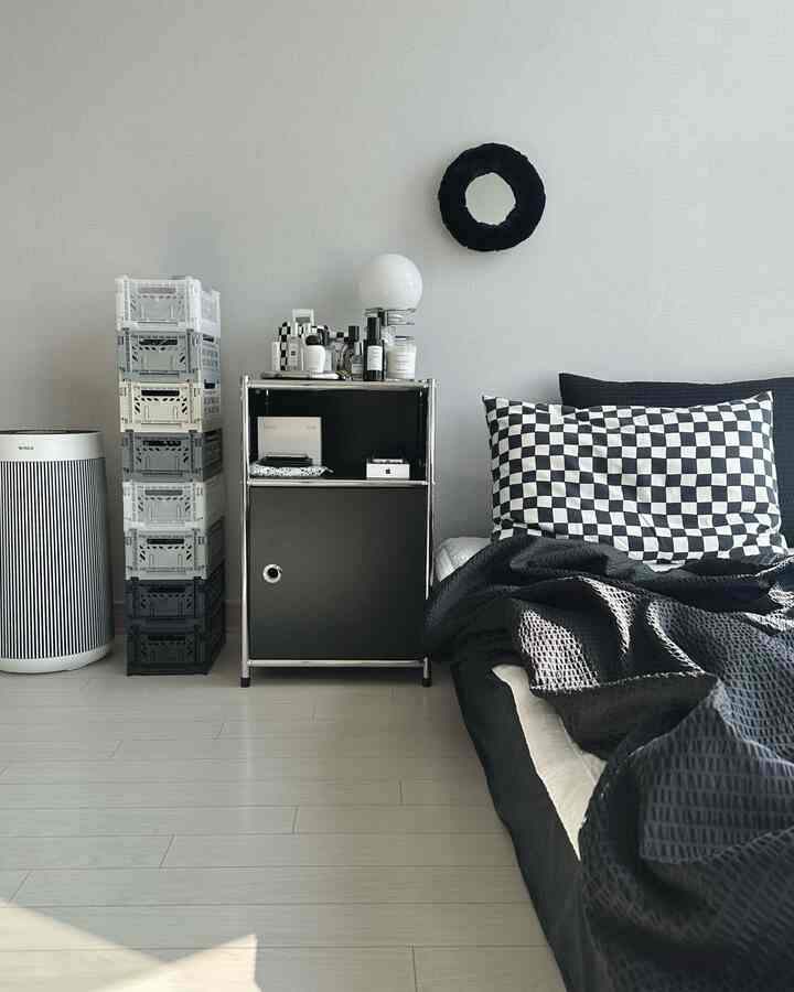 Monotone bedroom featuring a black storage cabinet and stacked folding boxes in a clean, simple space