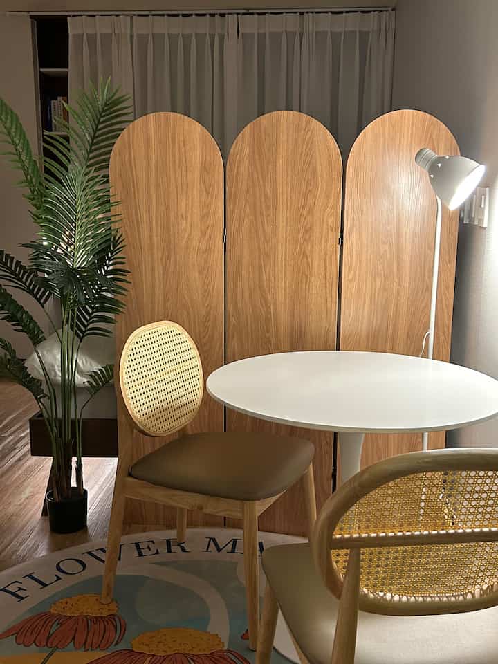 Natural wood tone living room dining area featuring a round white table and rattan-back chairs with a cozy atmosphere