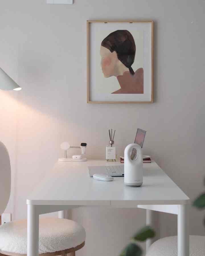 明るい白を基調とした寝室、シンプルでモダンなインテリアにホワイトデスクとラップトップ、ディフューザー、ブークレチェアが配置された空間