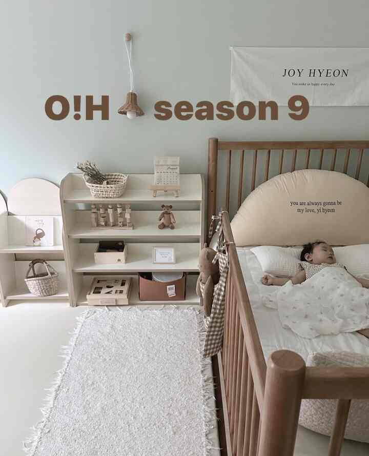 ナチュラルなウッドトーンとベージュの赤ちゃん部屋、ベビーベッドと収納棚、白いラグが落ち着いた雰囲気を演出