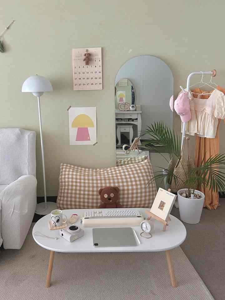 White and beige toned living room featuring white coffee table and sofa, large mirror, and green plant creating a cozy atmosphere