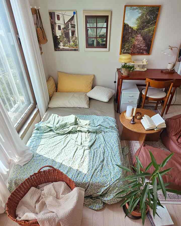 ナチュラルトーンの小さな部屋、一人暮らし向けのベッド、木製のデスクとコーヒーテーブルが配置された雰囲気のある空間