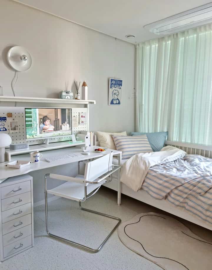 White and blue toned kids' room featuring desk and bedding with a clean, bright atmosphere