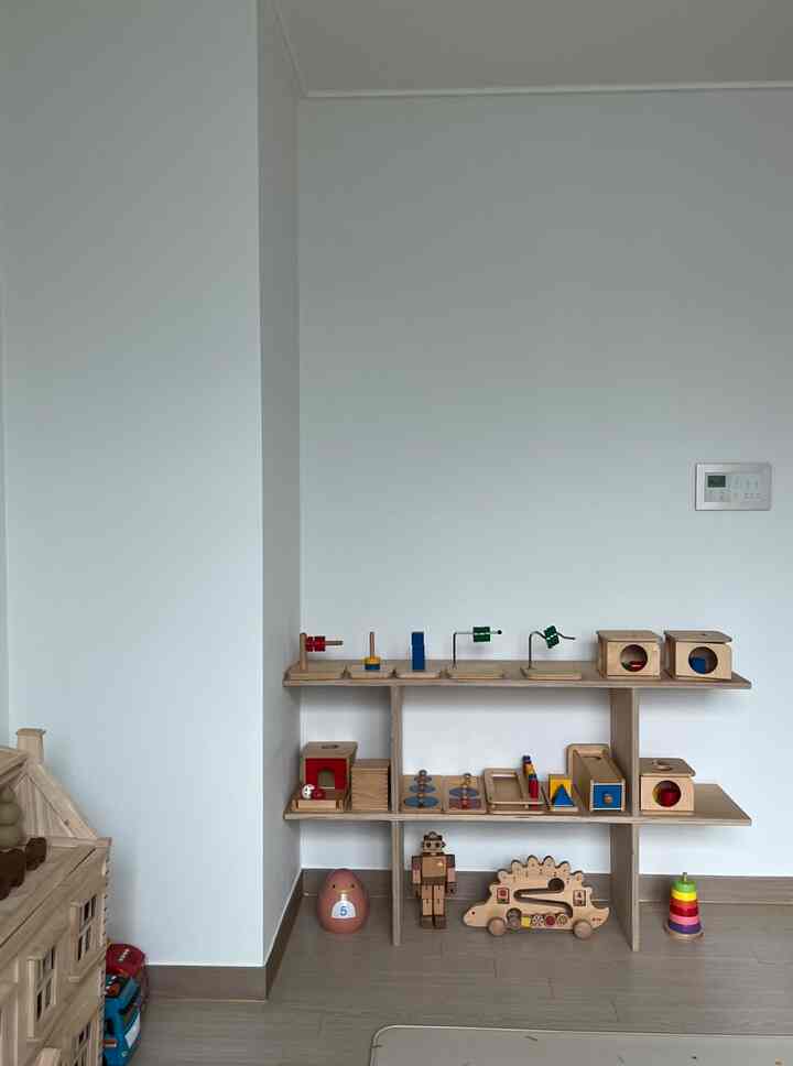 ナチュラルな木目調と白を基調とした子供部屋、中央におもちゃ収納棚を配した落ち着いた雰囲気のインテリア