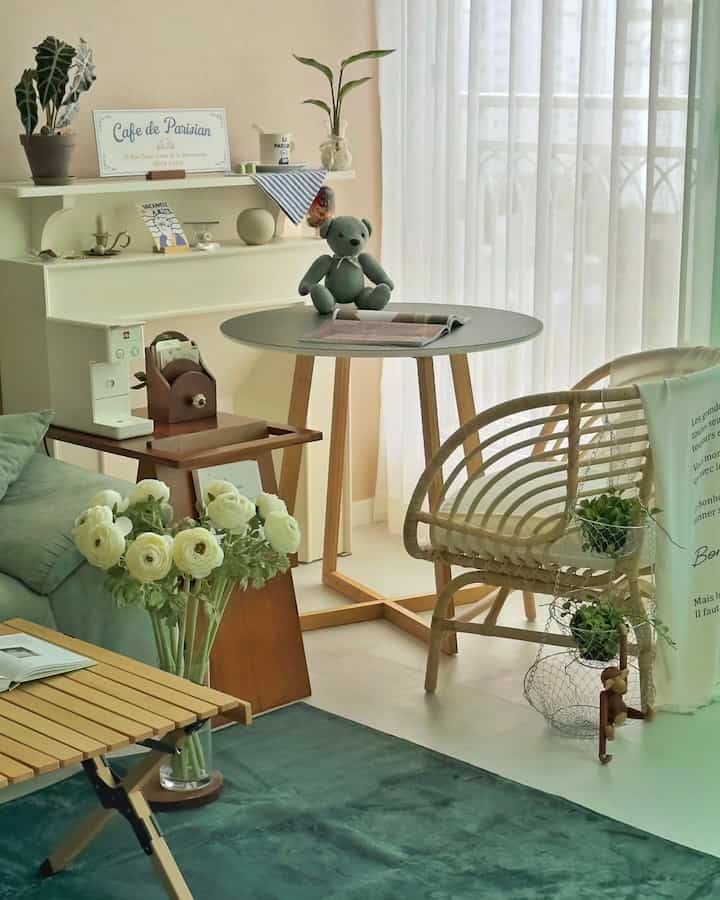 ナチュラルな木目調とベージュを基調とした居心地の良いおうちカフェ、丸テーブル、ソファ、シフォンカーテンが温かな雰囲気を演出