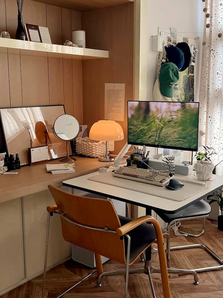 White and wood tone home office featuring a cozy desk setup with warm yellow table lamp and green plants