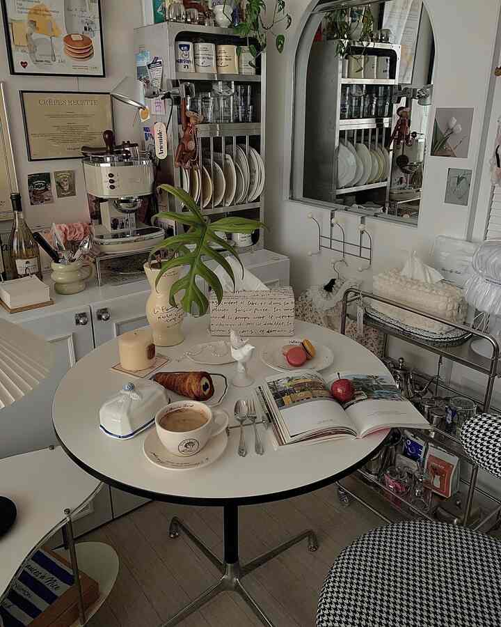 白と茶色のトーンの小さなおうちカフェ、ミッドセンチュリーモダンスタイルの丸いテーブルとハウンズトゥース柄の椅子が配置された雰囲気のあるインテリア