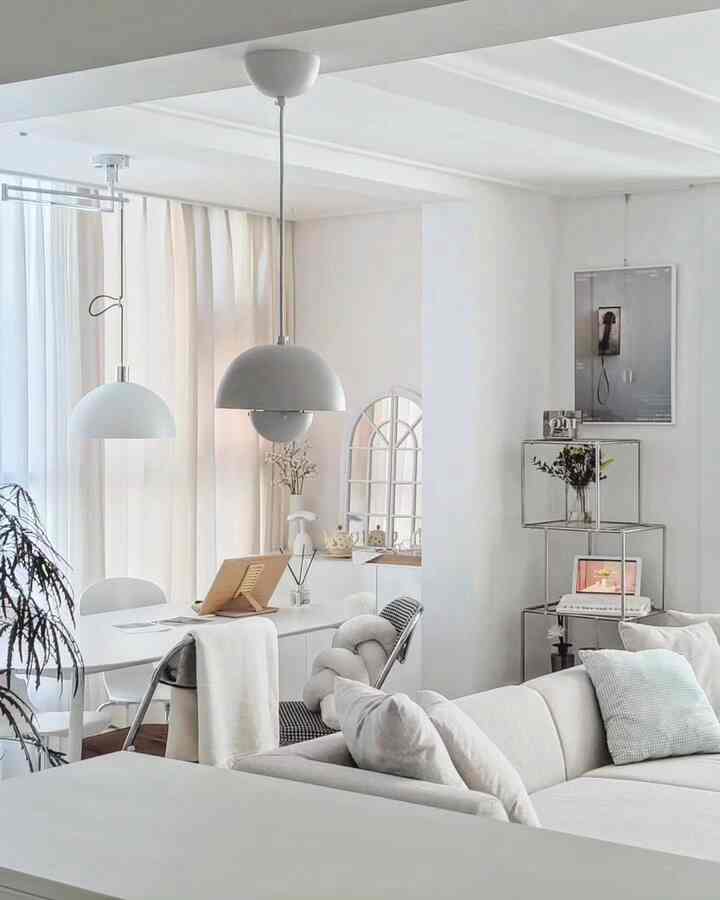 Bright white-toned living and dining space featuring modern modular sofa and pendant lights with a clean, minimalist atmosphere