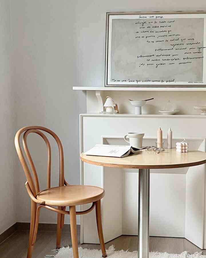 Natural modern home cafe space with beige-toned round dining table and curved wooden chair in neutral tones