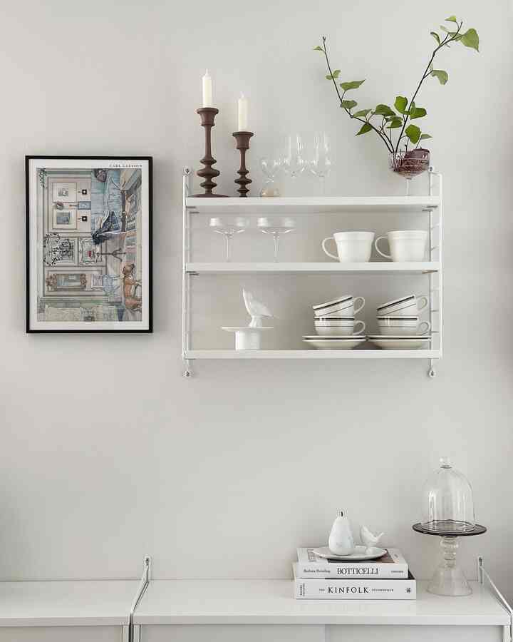 White-toned wall shelf arranged with neatly placed cups and decor, featuring a simple Nordic style space