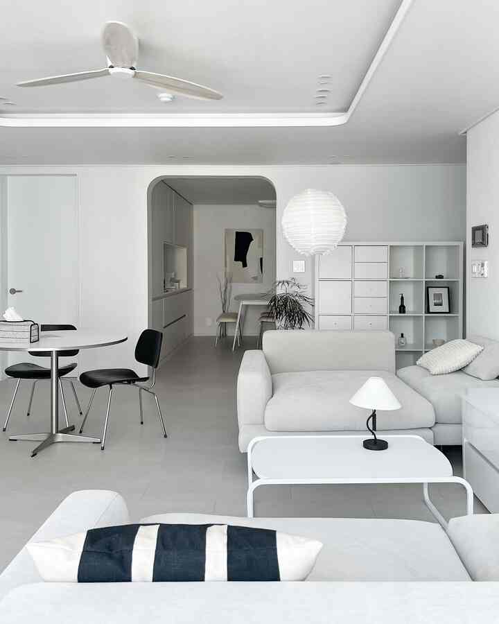 Bright white-toned living room featuring minimalist sofa and IKEA KALLAX bookshelf in a modern interior