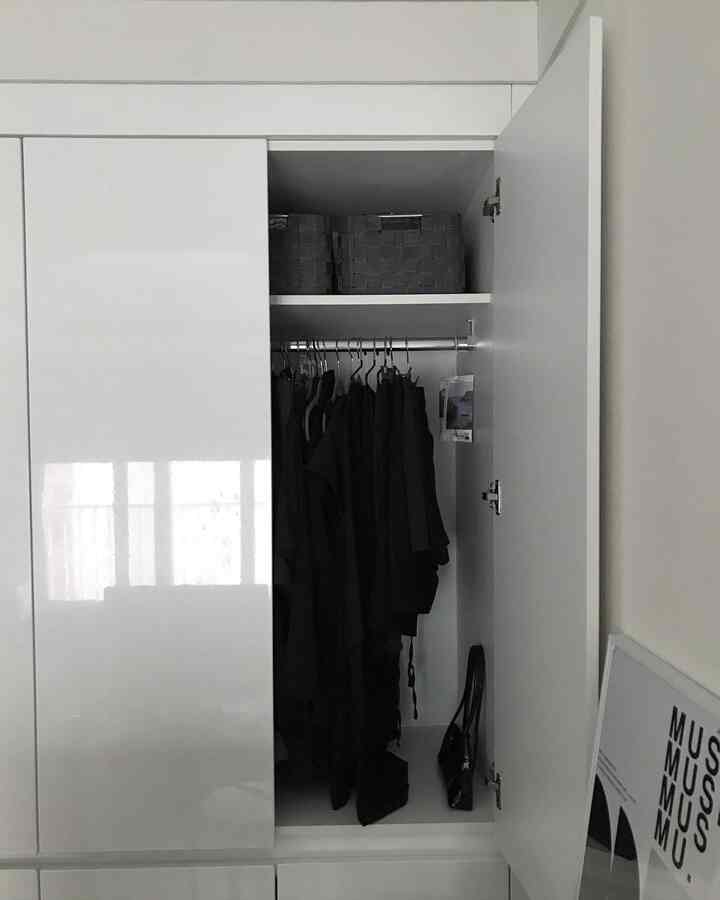 白と黒のモノトーン配色で清潔感あるクローゼット、整理された黒い衣服と収納バスケットが置かれた実用的な空間