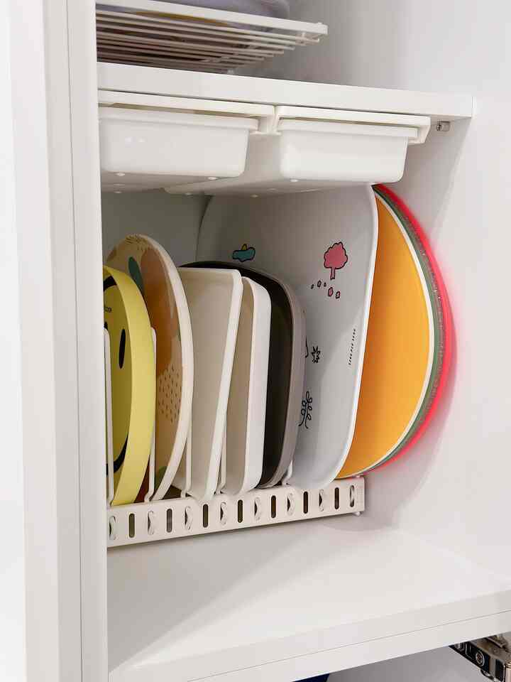 White-toned kitchen storage cabinet interior featuring neatly organized trays standing upright