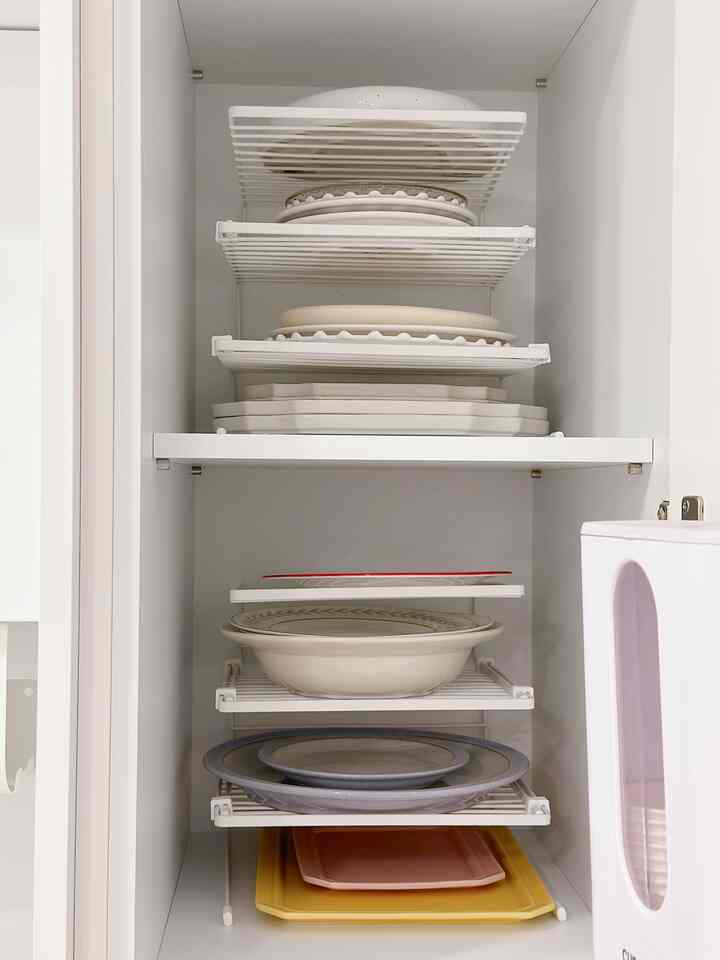 White-toned kitchen cupboard featuring neatly organized plates of various sizes and shapes on multiple shelves