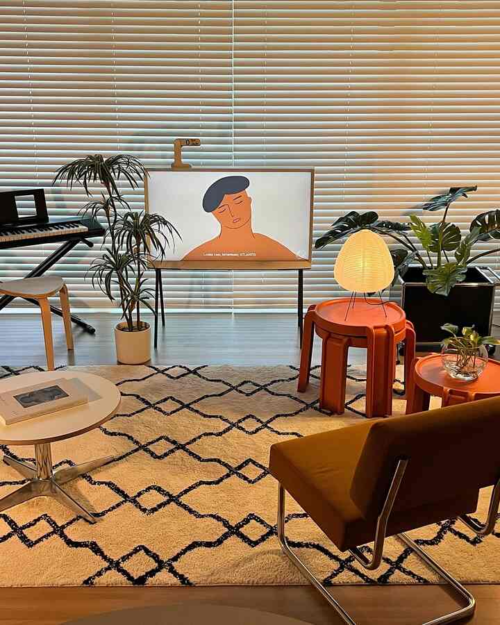 Beige and wood tone living room featuring mustard sofa, orange tables, lamp, and plants in a modern styled atmosphere