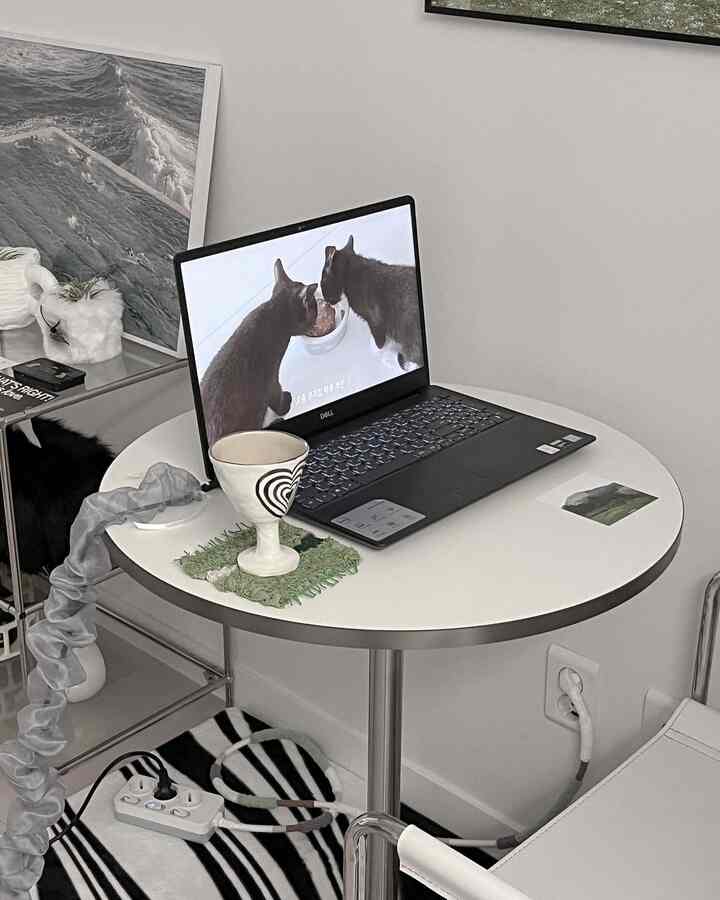 白とシルバーの落ち着いた色調のコンパクトなおうちカフェ空間、円形テーブルにノートパソコンとカップが置かれた雰囲気のあるインテリア