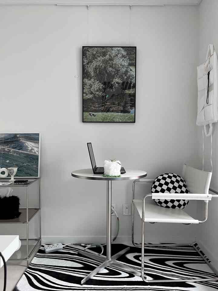 白とシルバーのトーンで統一されたモダンなホームオフィス空間、丸テーブルとシンプルなアームチェアが配置された清潔感のあるインテリア