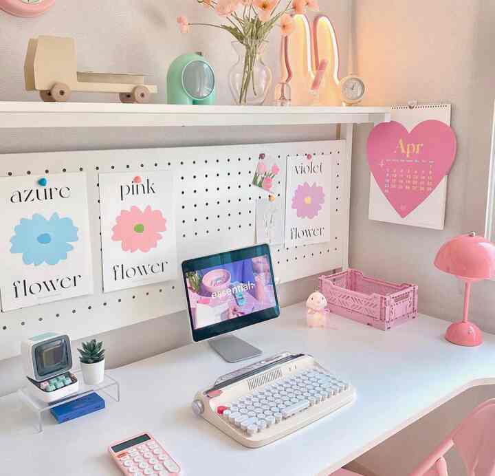 白とピンクのトーンのホームオフィス、レトロなキーボードとiPadが配置された印象的なインテリア