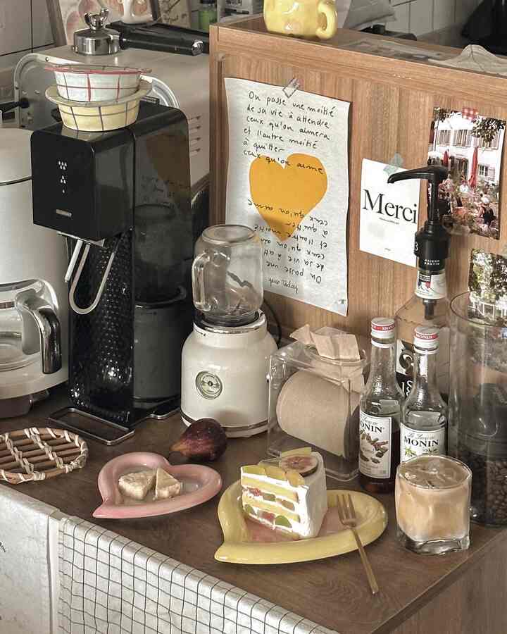 ブラウンの木目調キッチンカウンターにおうちカフェ用品とハート型の皿が置かれた雰囲気のある空間